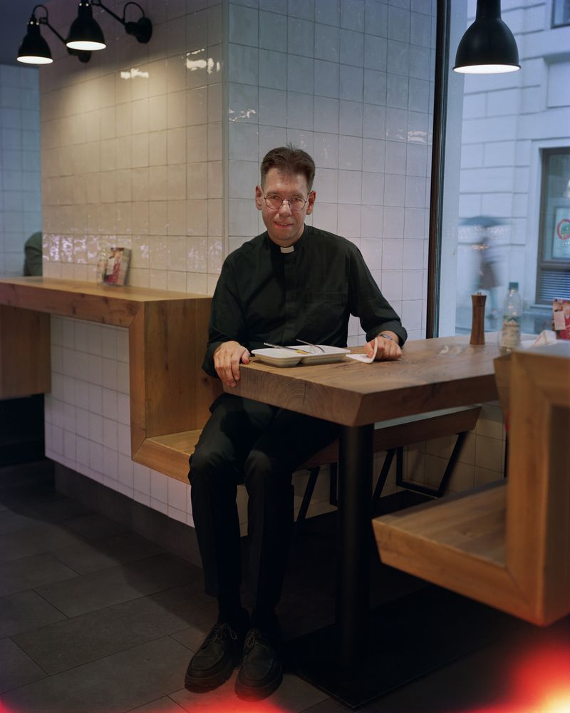 © Dawn Kim - Father John with a schnitzel lunch, Vienna, Austria, 2023