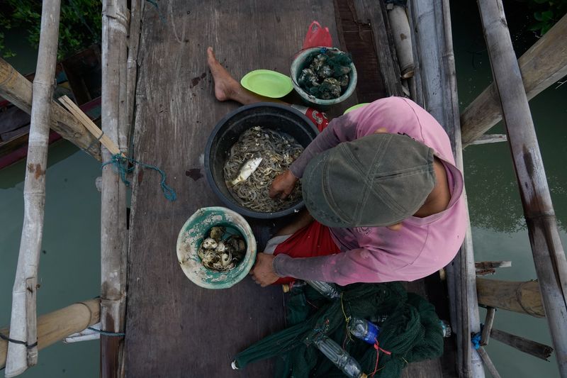 © Pakak Banak - A resident fishes amid seawater flooding that has inundated his home and village.