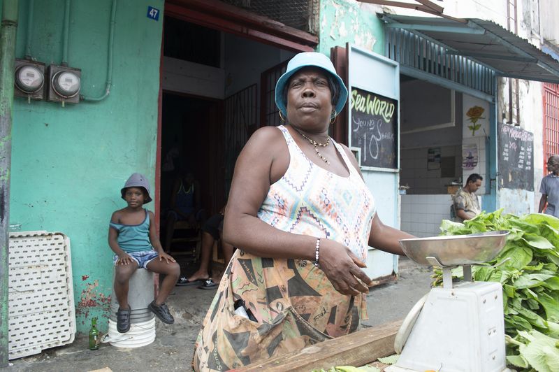 © Johanne Rahaman - A vegetable and fish vendor at the George Street Market - her granddaughter in the background.Port of Spain, Trinidad 2015