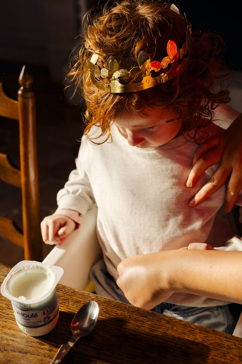 © Olivia de Villaine - Parastoo settles a child in a paper crown at the table. In France, she works as a babysitter alongside her studies.