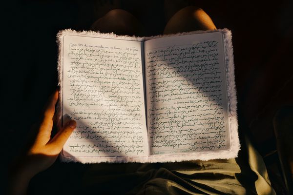 © Olivia de Villaine - Parastoo's diary open on her lap, written in Persian. The first line reads: Day 594 of my new life in France.