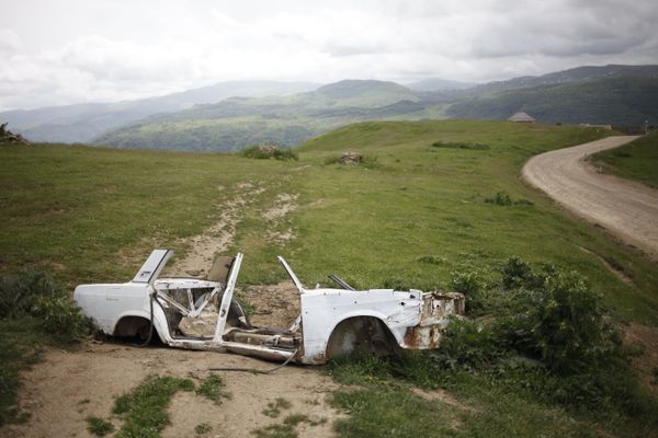 © EDUARD KORNIYENKO - A view on the remains of body shell of Lada car near the road in the mountains of Dagestan.