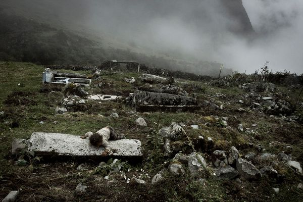 © Max Cabello Orcasitas - A girl lies on the grave of her relative during their funeral.