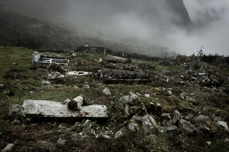 © Max Cabello Orcasitas - A girl lies on the grave of her relative during their funeral.