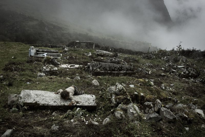© Max Cabello Orcasitas - A girl lies on the grave of her relative during their funeral.