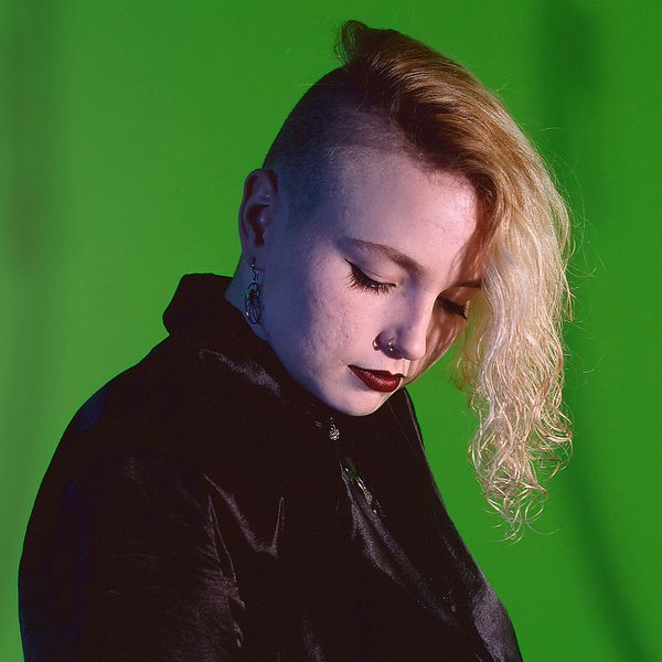 © Steven Edson - Portrait of Goth woman with partially shaved head looking away from camera.
