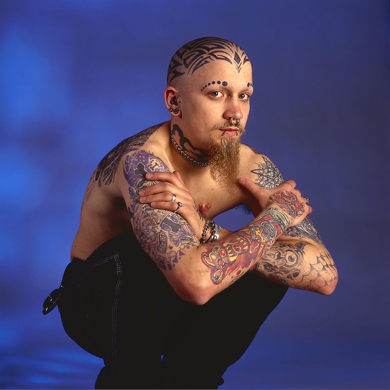 © Steven Edson - Young man with beard has many tattoo's and piercings across his body.