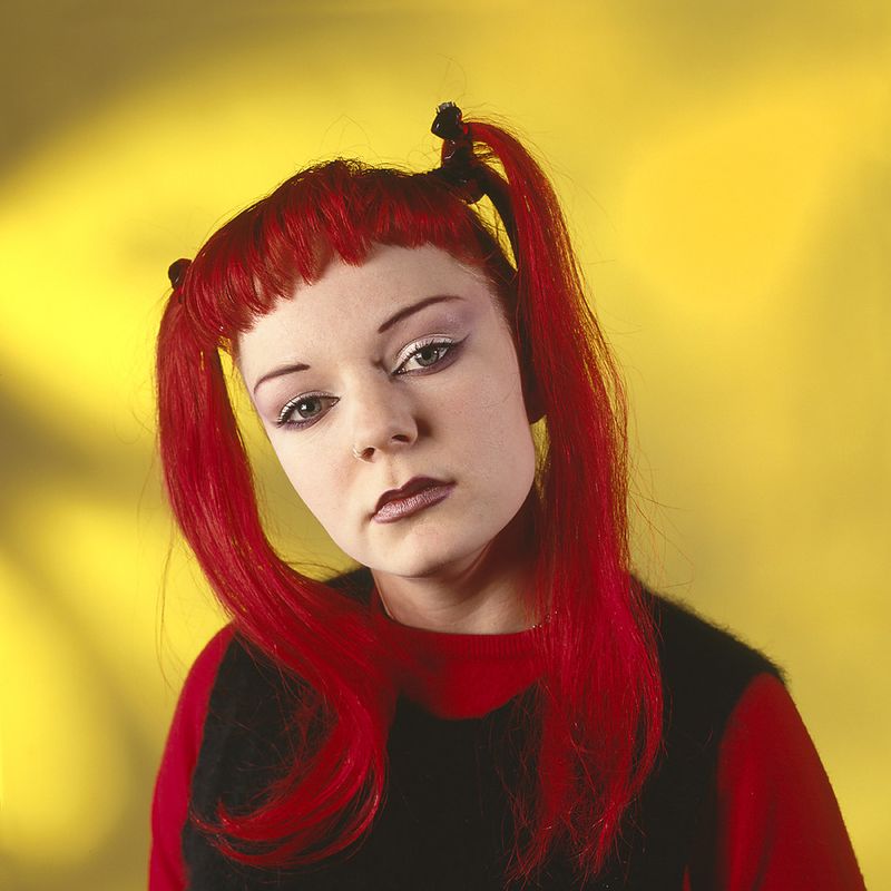 © Steven Edson - Young woman with bright red hair against a yellow background