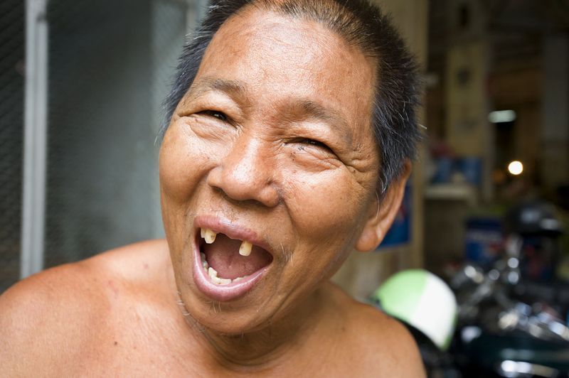 © Steven Edson - Man with big toothless smile in the food markets of Bangkok, Thailand