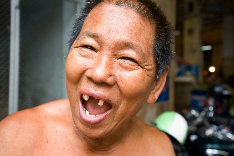 © Steven Edson - Man with big toothless smile in the food markets of Bangkok, Thailand