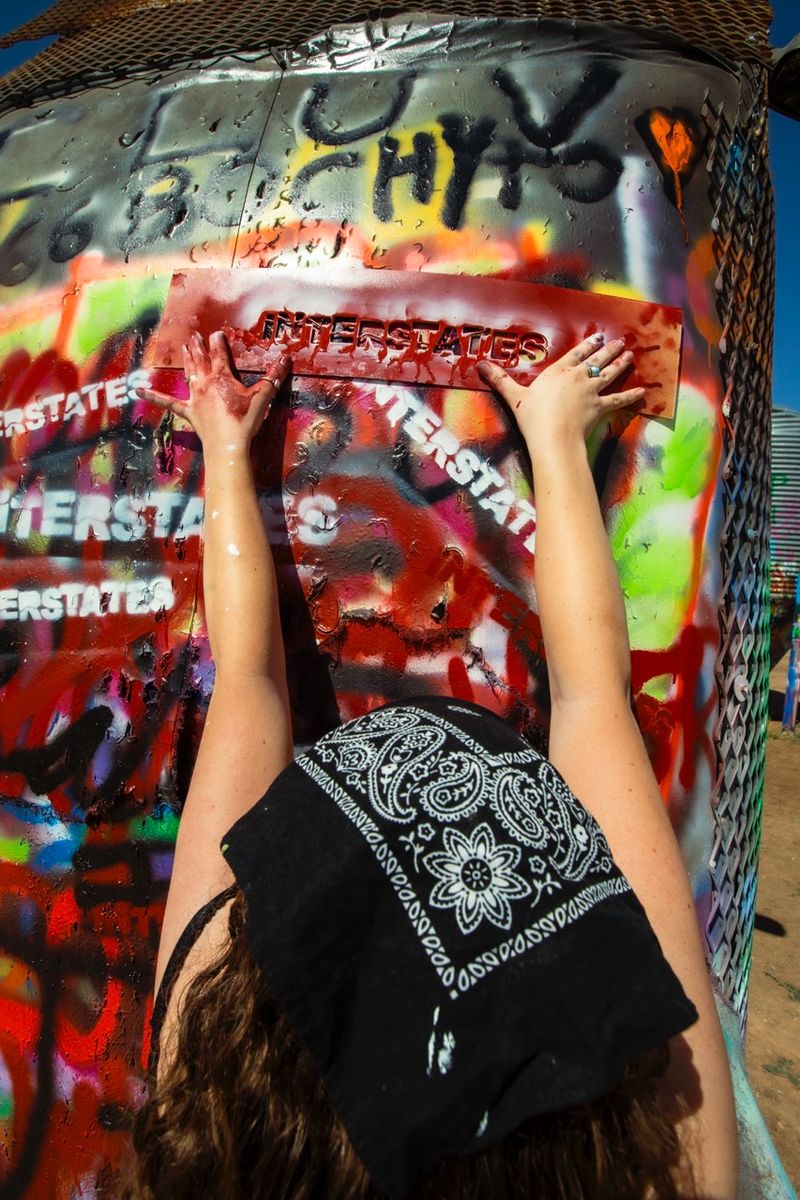 © William Hohe - Charlotte spray paints a junk car outside of Amarillo, TX.