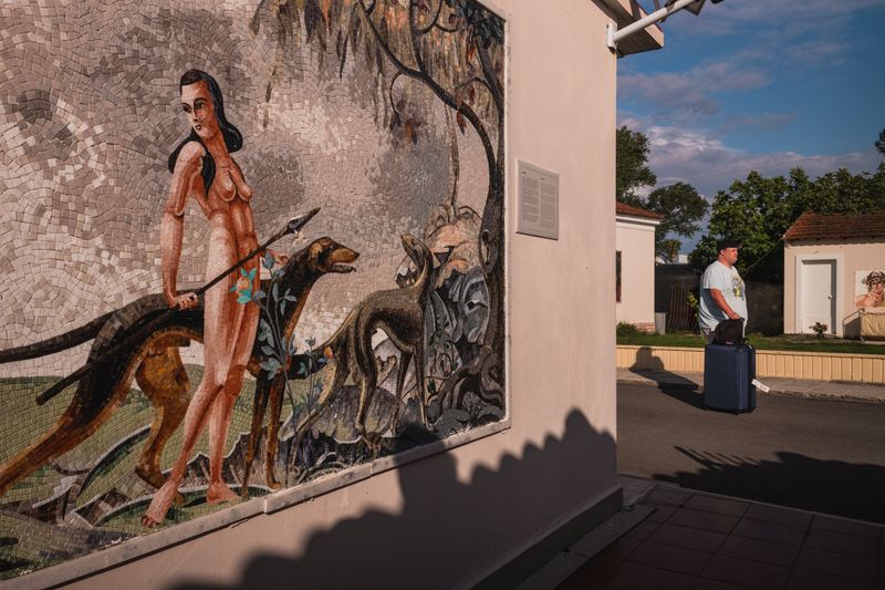 © Christopher Jones - Man with suitcase and muralKavos, Corfu.A man walks with a suitcase past a mural outside a beach hotel.