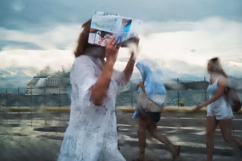 © Christopher Jones - Woman with map in rainCorfu Port.A woman holds a folded map above her head during a rainstorm near the port.