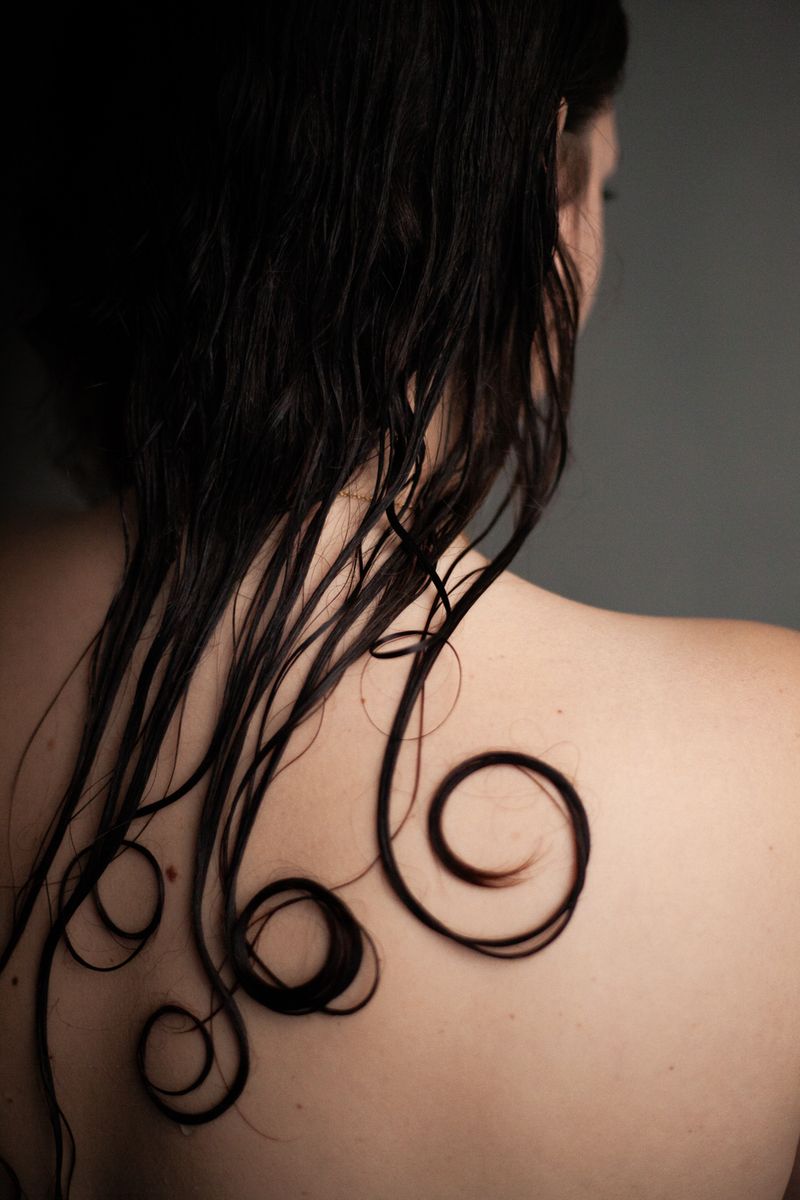 © Susanna Fiona Murray - Spiral of hair curls against the skin of the back.