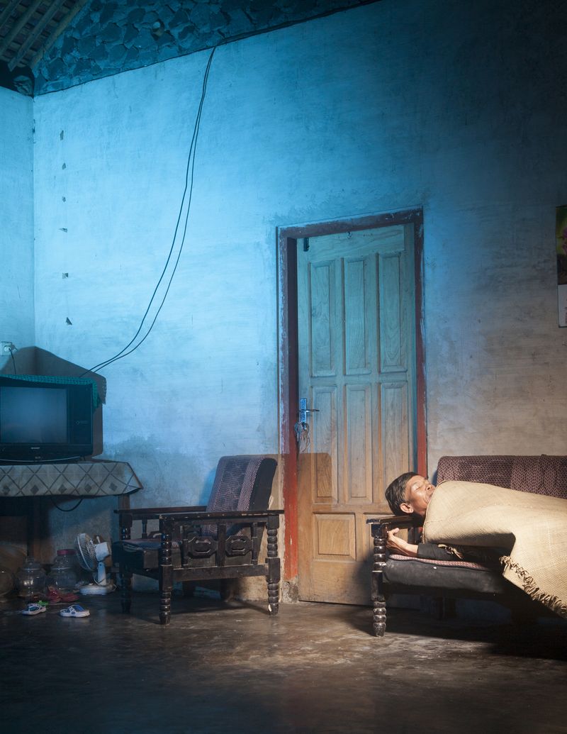 © Hahn Hartung - Bapak Gimin in his living room, showing how his father "hid" from a pyroclastic flow of an eruption of Mt. Merapi.