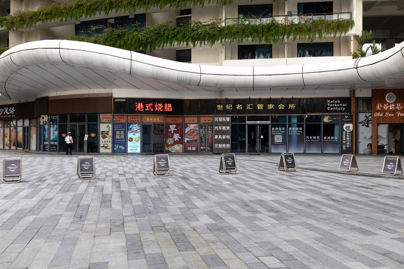 © Francesca Pompei - A lonely worker in front of some Chinese shops in the hill of Forest City.