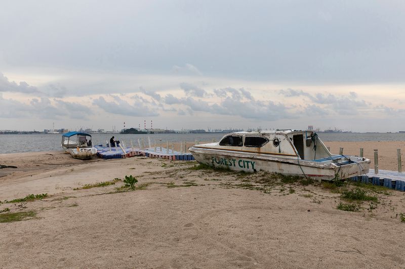 © Francesca Pompei - A rusted boat with the local logo in the abandoned beach of Forest City with a local fisherman.