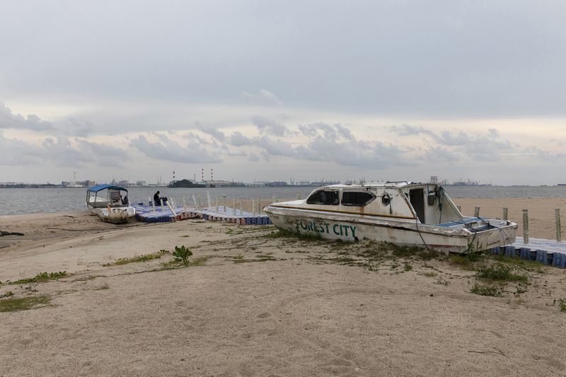 © Francesca Pompei - A rusted boat with the local logo in the abandoned beach of Forest City with a local fisherman.