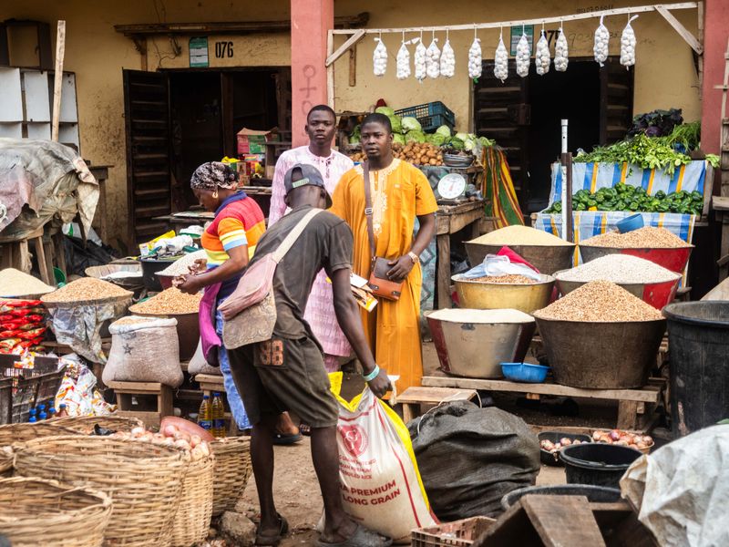 © Adegoke Kolawole - Stall 076A grain trader watches as a customer loads a sack of rice at Stall 076, Bodija Market, Ibadan, 2025.