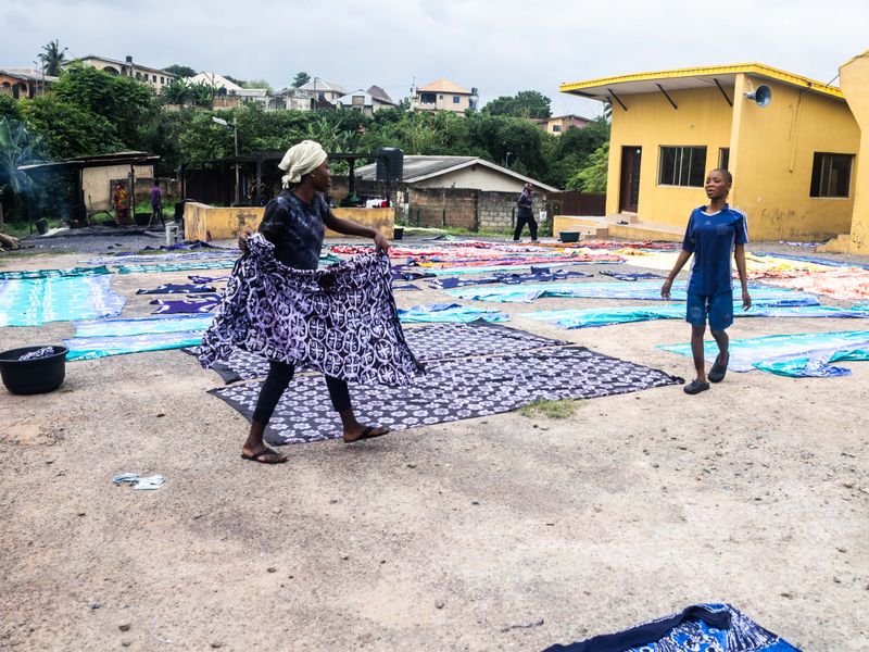 © Adegoke Kolawole - Laying OutA worker opens a finished length of adire across the drying ground, Abeokuta, 2025.