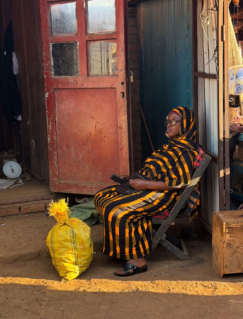 © Zahra Farajasri - Kigali, Rwanda, 2026 - A woman resting beside her stall at a market in Kigali.