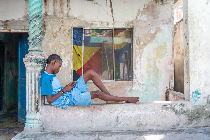 © Gaston Zilberman - A kid on his phone while the wall behind him has been cracking for years.