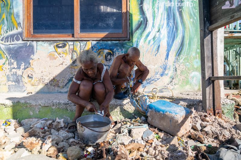 © Gaston Zilberman - Hidden in the shade, an elderly couple cleans the fresh fish brought in that morning.