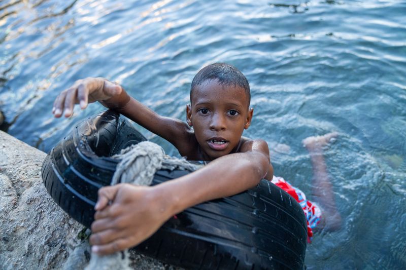 © Gaston Zilberman - A kid in the water, holding on to an old tire used for parking the boats.
