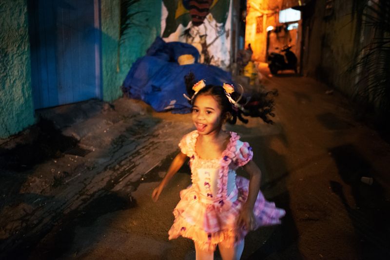 © Sabine van Wechem - Girl from the neighbourhood is running around through the alley during festina junina, an annual celebration day.