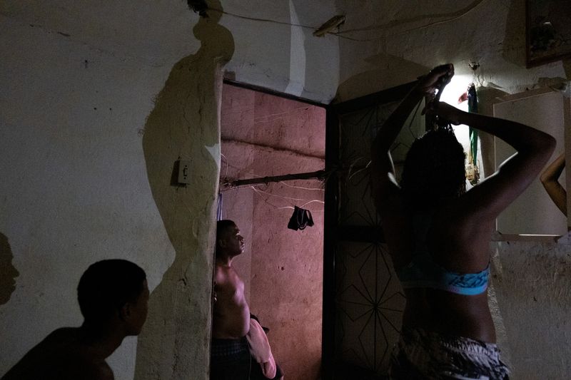 © Sabine van Wechem - All the lights went out in the favela, Thay is trying to get her hair nice before going out.