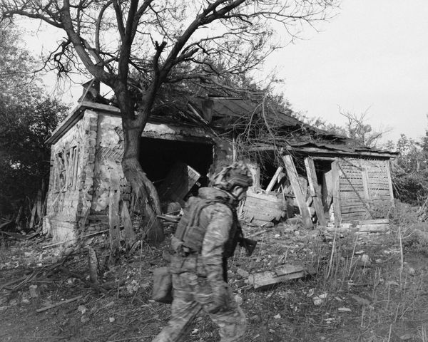 © David Hadland - A Ukrainian soldier walks past a house in a frontline village in Sumy Oblast, destroyed by a Russian glide bomb. 2025.
