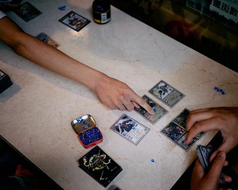 © Chung-wai Wong - Teenage boys playing anime card games in a small shopping arcade.