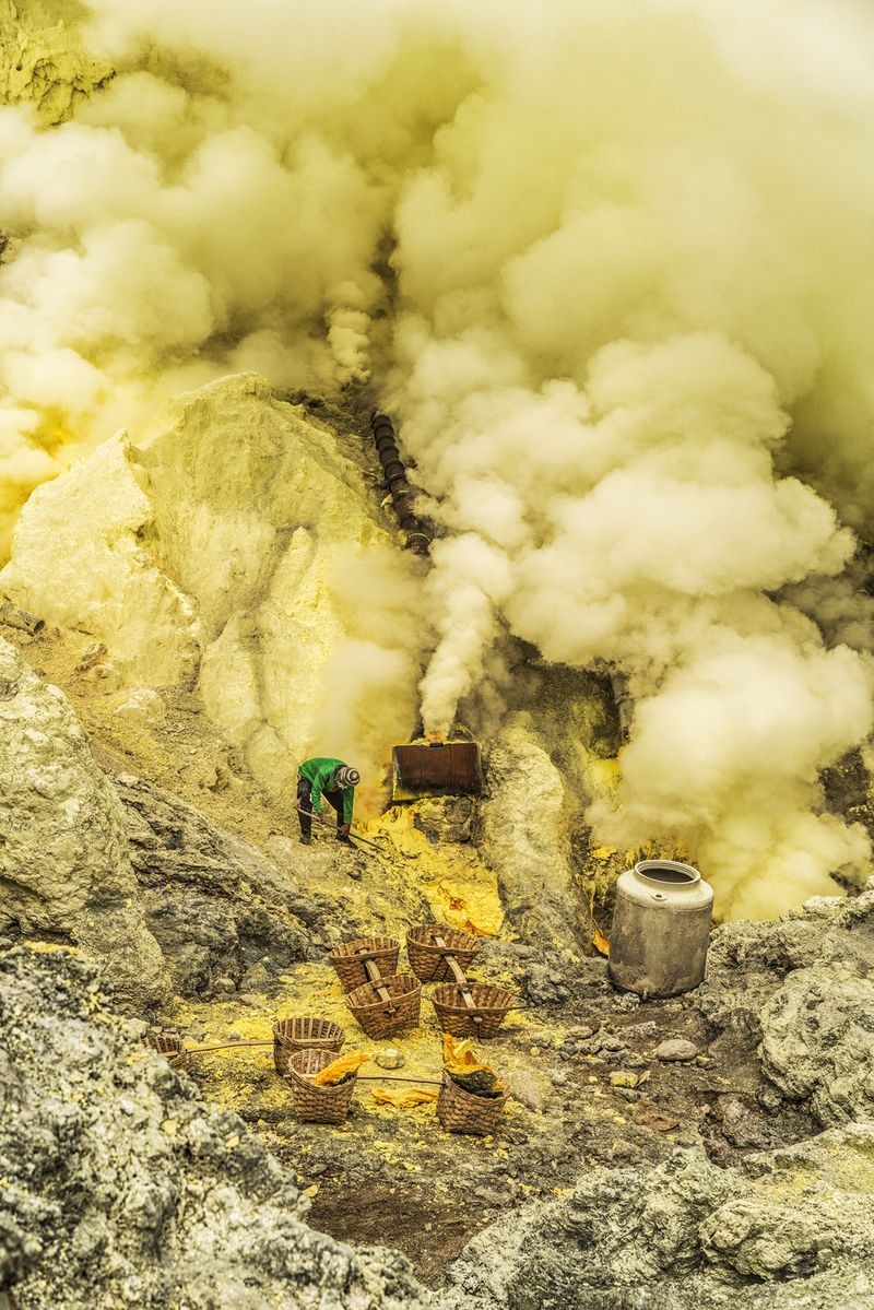 © Manolo Ty - A miner works in the acidic fumes of the vulcano to extract hardened sulfur blocks.