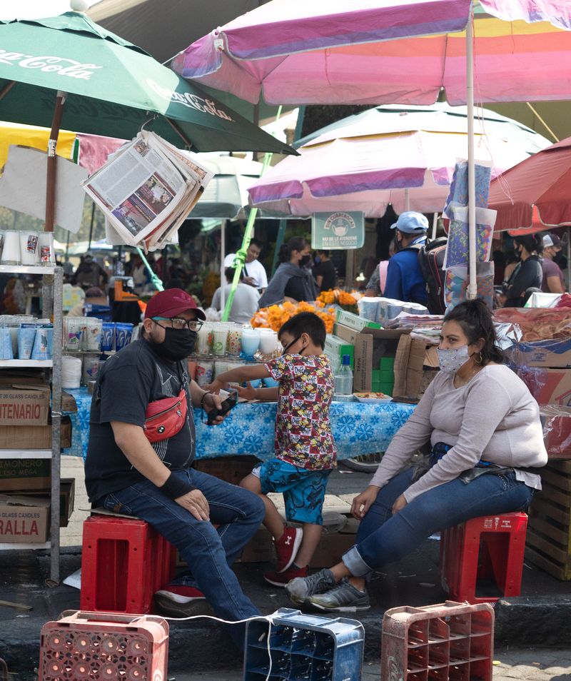 © Roxanne Munson - A man and a woman sitting down selling candles with a little boy in between them.