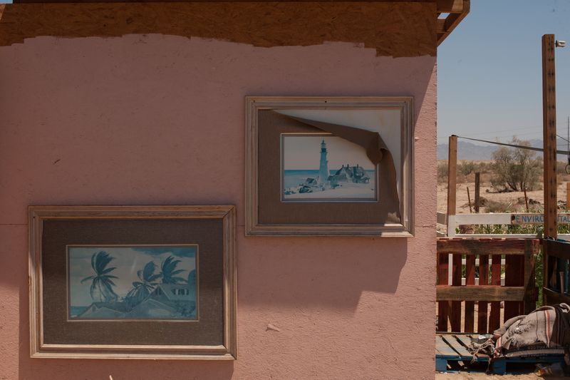 © Jason Houge - Images of paradise adorn the wall of a structure at B-Side camp, a half mile from the cold shower; Slab City, USA 2018