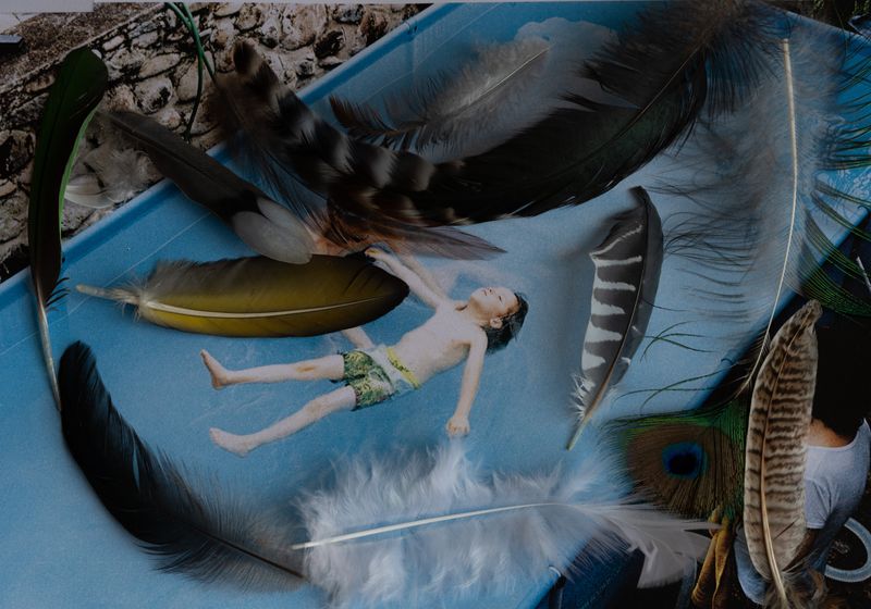 © María García - Physical collage with a 35 mm printed photograph of my son swimming, on which I placed part of his collection of feathers.
