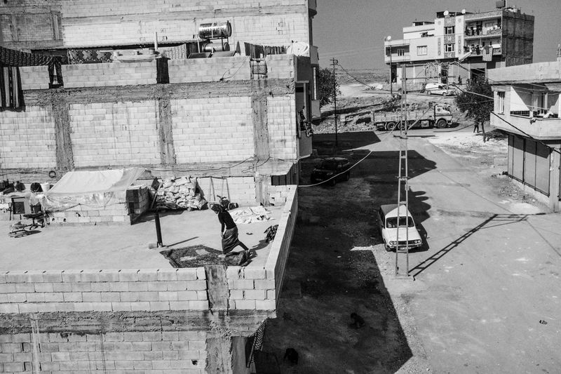© Emin özmen - A woman stands on a carpet in her roof where mostly Syrian refugees lives in Gaziantep Turkey, November, 2016.