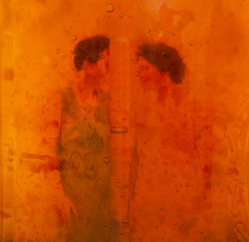 © Lauren Bertelson - Preserves 4, 2023, 30” x 30”, Pigment print. Preserves 4 is a photograph of a family photograph suspended in peach jam.