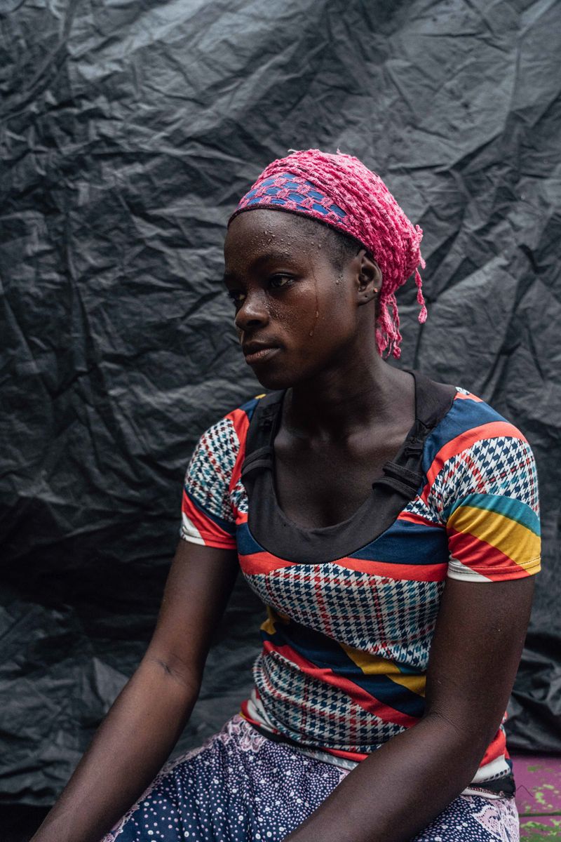 © Natalija Gormalova - Rahina, who works as a kayayei, pauses to rest after carrying a heavy bale under the intense heat of Accra.