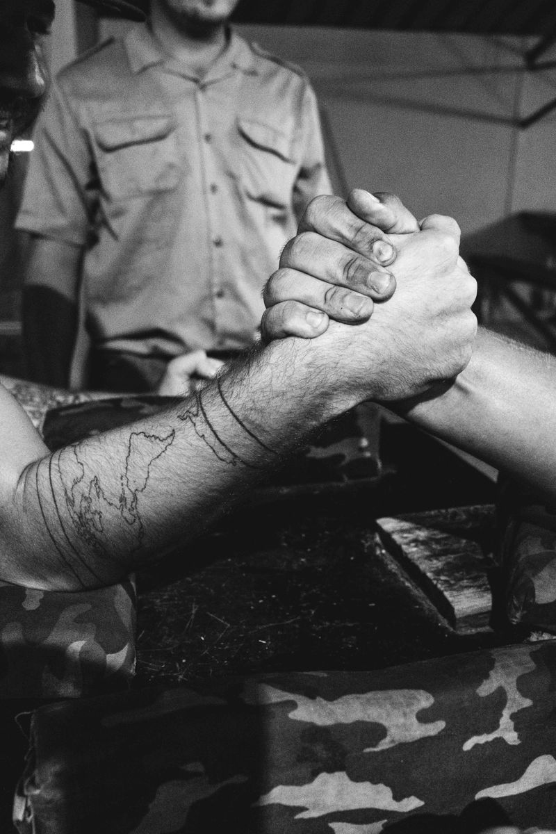 © Nadia Ettwein - Two men arm-wrestle at a local bar, engaging in a casual sporting contest.