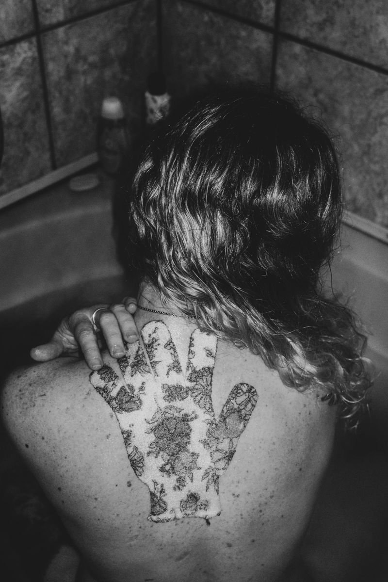 © Nadia Ettwein - I miss you, 2025. Self portrait of my back with a hand shaped floral cloth.