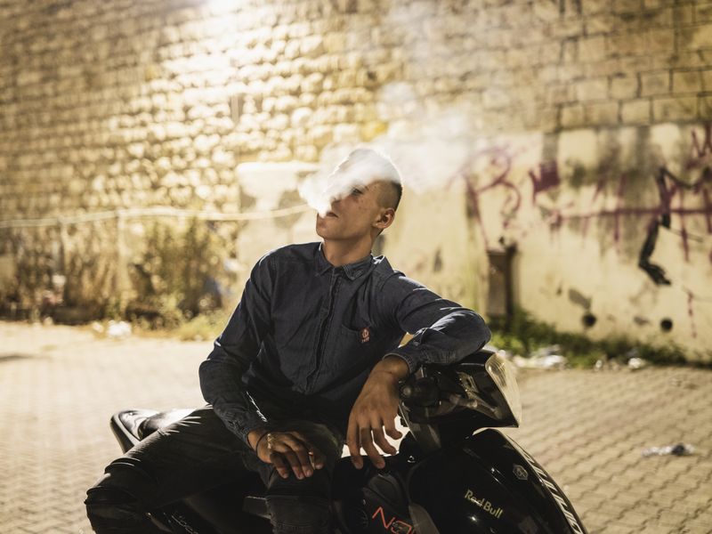 © Sebastian Wells - Danilo smokes on his motorbike. „He´s famous at the police office“, a few friends of him tell me. Augusta, August 2019.