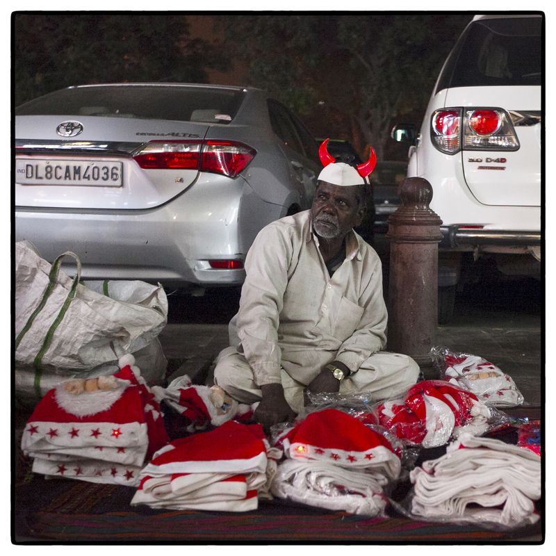 © Vijay S. Jodha - An elderly man wearing a novelty over his traditional cap, waits for customers.