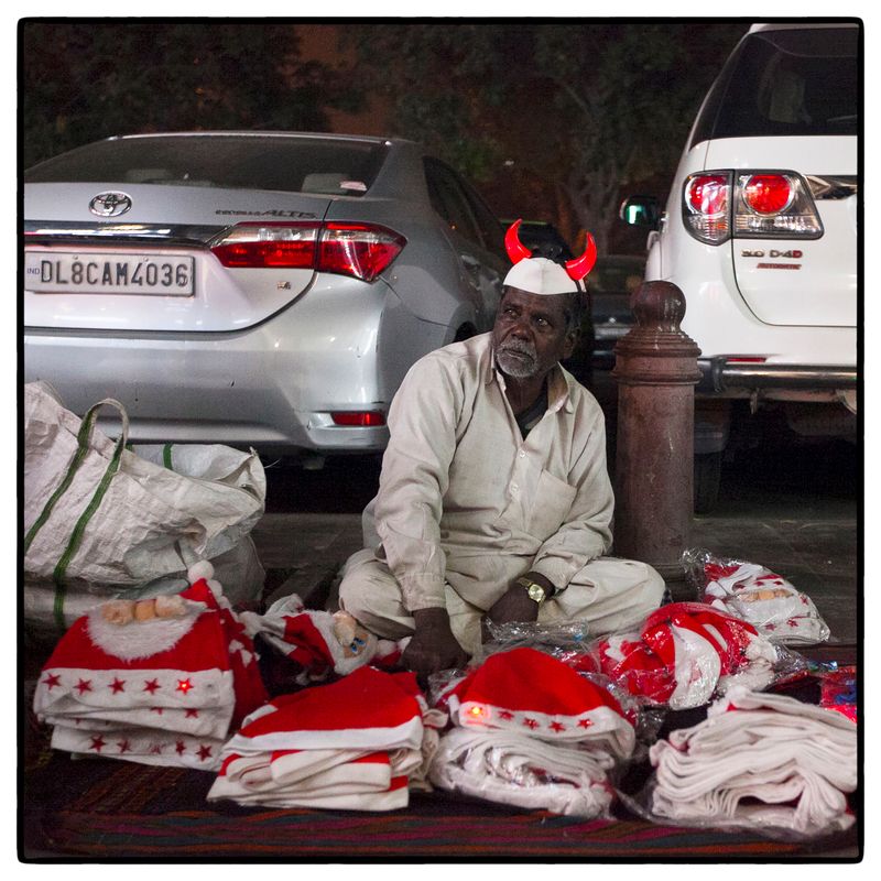© Vijay S. Jodha - An elderly man wearing a novelty over his traditional cap, waits for customers.