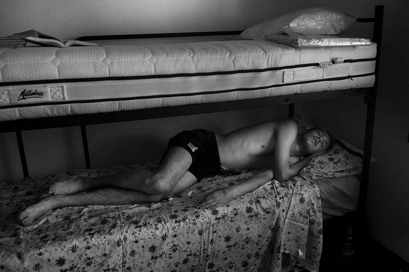 © Maria Giulia Trombini - Mark sleeps late in the morning in a shared room in the CAS house. Verona, Italy.
