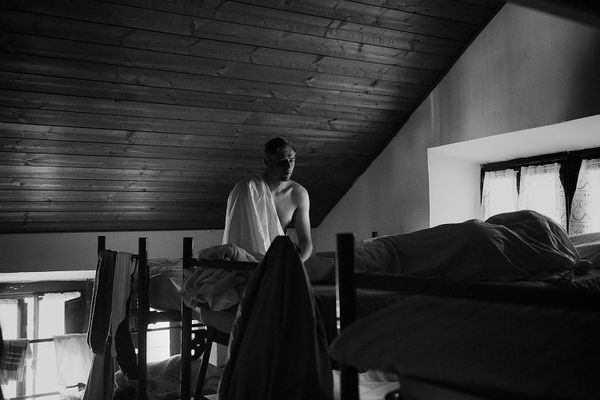 © Maria Giulia Trombini - Dima(L) sits on the bed in the shared room, Max(R) sleeps next to him. Verona, shared house, Italy.