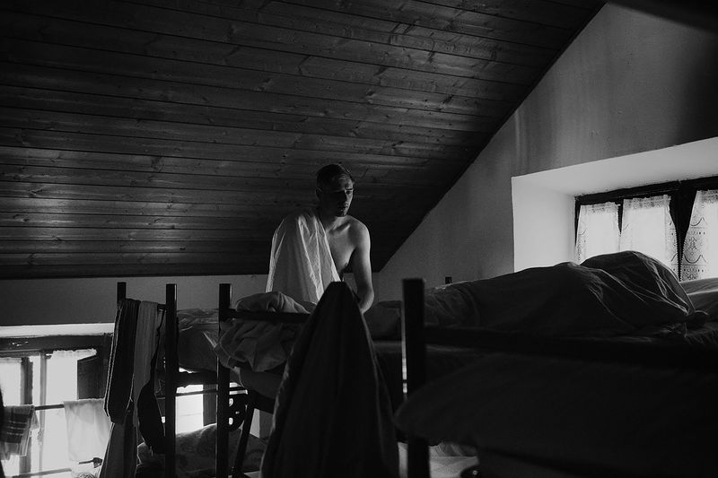 © Maria Giulia Trombini - Dima(L) sits on the bed in the shared room, Max(R) sleeps next to him. Verona, shared house, Italy.