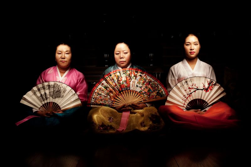 © Flore-aël SURUN - Three Mudangs (shaman women) pose with the ritual fan, on which are represented auxiliary spirits.Seoul, South Korea.