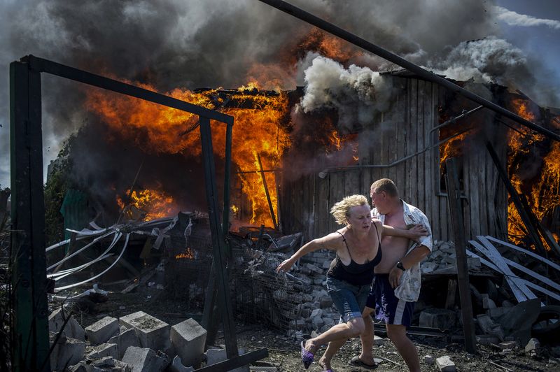 © Valery Melnikov - Civilians escape from a fire at a house destroyed by air attack in the Luhanskaya village