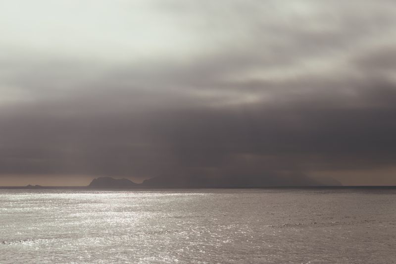 © Gianfranco Suito - The gloomy island hides behind a cloudy landscape as the sun sets for a new day to begin again.